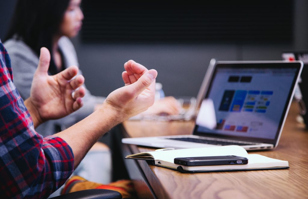 Person talking with colleagues with laptop open
